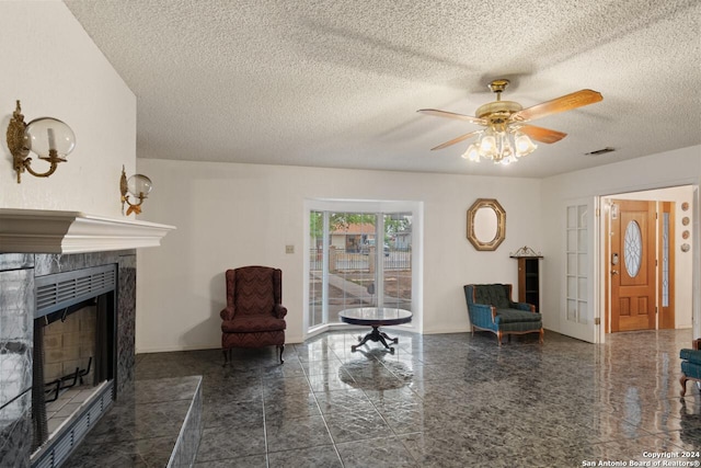 interior space featuring ceiling fan, a textured ceiling, and a tiled fireplace