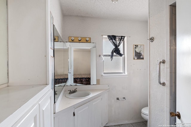 bathroom with tile patterned flooring, vanity, a textured ceiling, and toilet