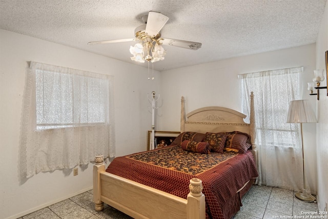 bedroom with ceiling fan, light tile patterned floors, and a textured ceiling