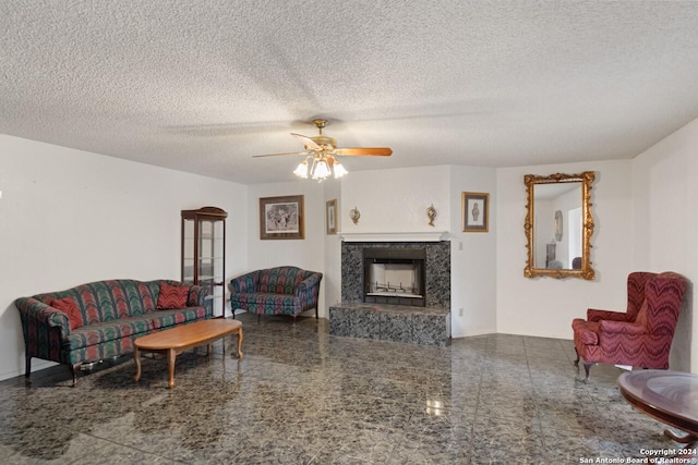 living room with a premium fireplace, ceiling fan, and a textured ceiling