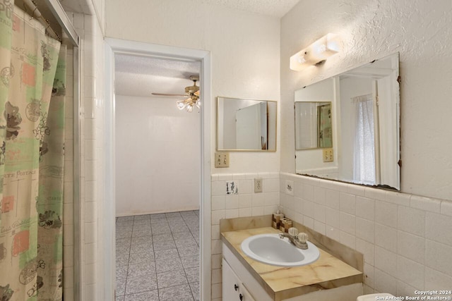 bathroom with tile patterned flooring, a textured ceiling, tile walls, and ceiling fan