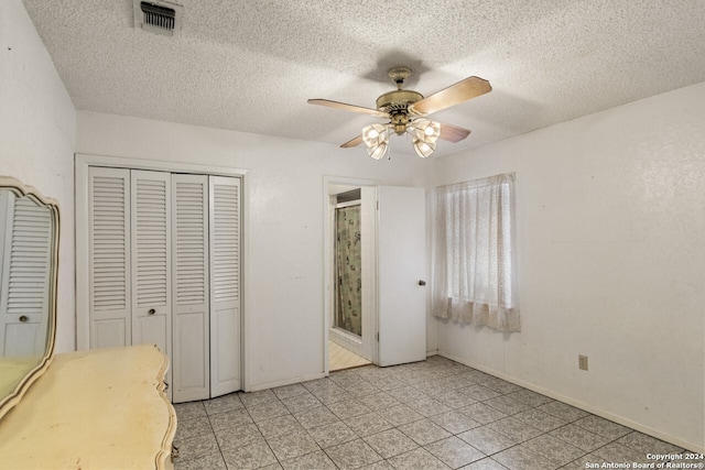 unfurnished bedroom with ceiling fan, light tile patterned floors, a textured ceiling, and a closet