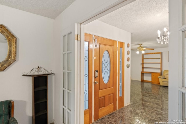 entryway with ceiling fan with notable chandelier and a textured ceiling