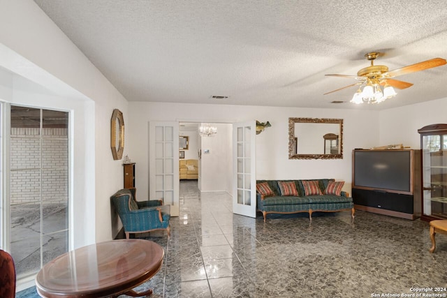 living room with ceiling fan with notable chandelier, french doors, and a textured ceiling