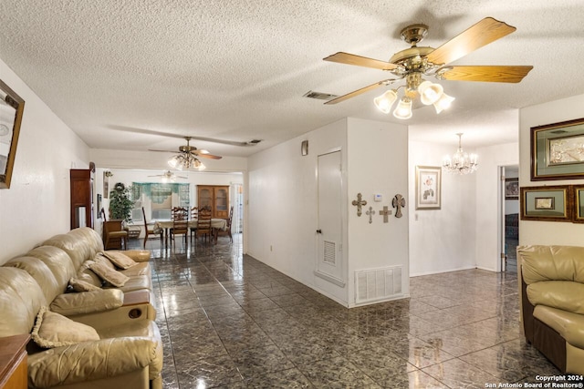 living room featuring ceiling fan with notable chandelier and a textured ceiling