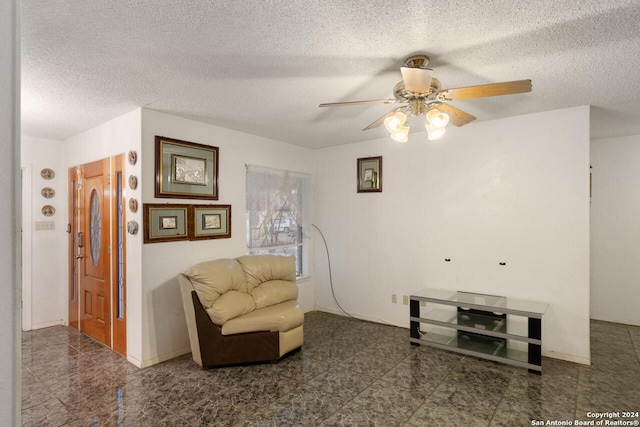 living area featuring ceiling fan and a textured ceiling