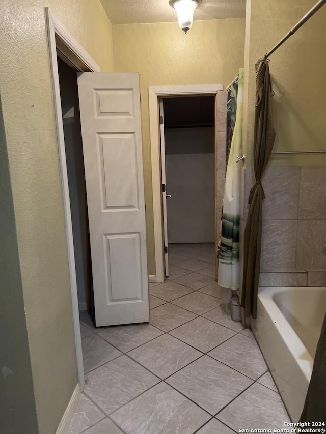 hall with light tile patterned floors and a textured ceiling