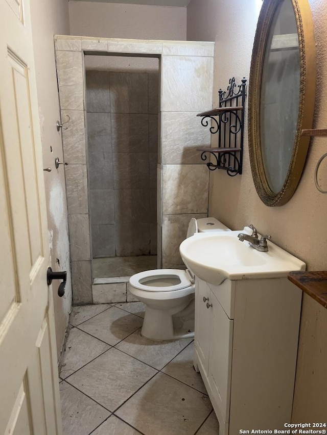 bathroom featuring tile patterned flooring, a tile shower, vanity, and toilet