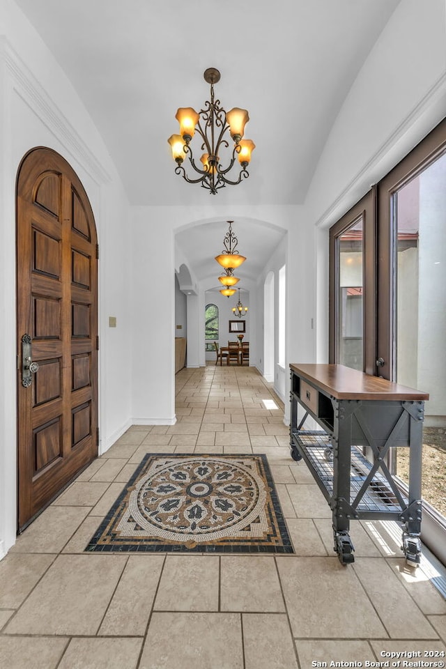 foyer with a chandelier and vaulted ceiling