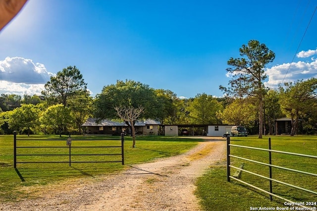 view of gate with a lawn and a rural view