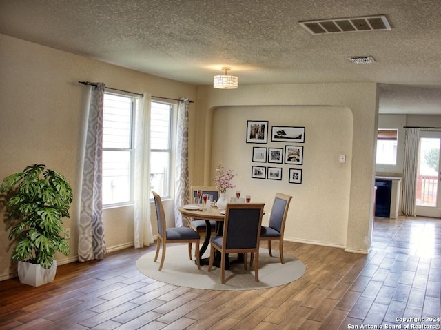 dining space featuring hardwood / wood-style floors, a textured ceiling, and a healthy amount of sunlight