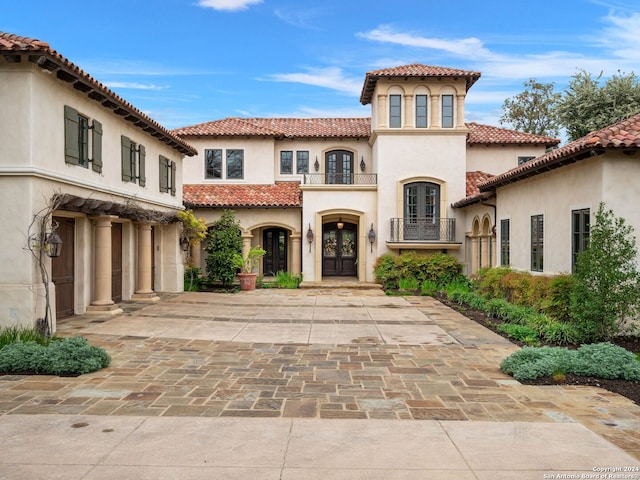 mediterranean / spanish-style house featuring french doors, a balcony, and a garage