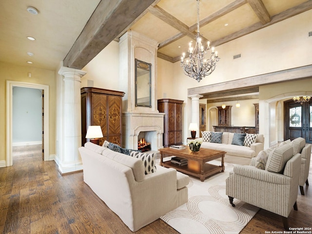 living room with decorative columns, a large fireplace, dark hardwood / wood-style flooring, and beamed ceiling