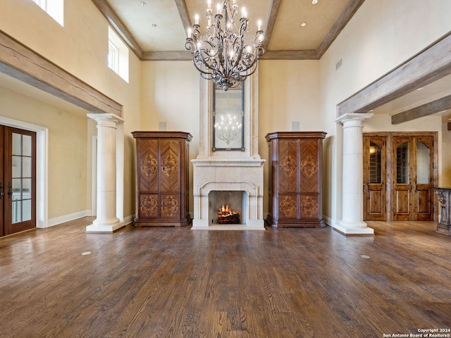 unfurnished living room featuring hardwood / wood-style floors, ornate columns, a fireplace, and a high ceiling