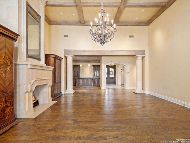 unfurnished living room with a fireplace, coffered ceiling, dark wood-type flooring, a notable chandelier, and beamed ceiling