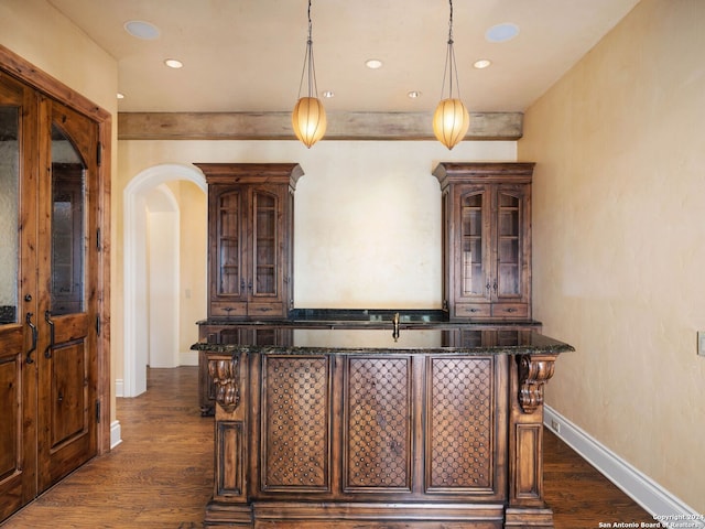 bar featuring dark brown cabinetry, decorative light fixtures, dark hardwood / wood-style floors, and dark stone counters