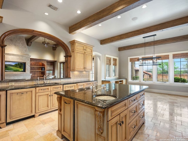 kitchen with pendant lighting, beam ceiling, sink, and a kitchen island with sink