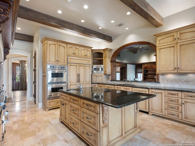 kitchen featuring built in appliances, decorative backsplash, a center island with sink, and beamed ceiling