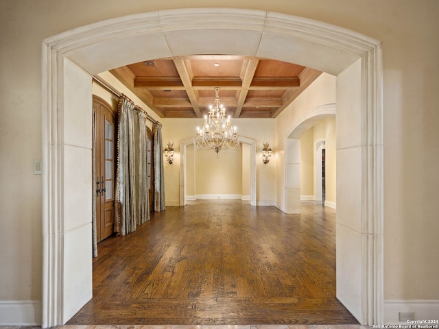 hall featuring beam ceiling, dark wood-type flooring, coffered ceiling, a chandelier, and ornamental molding