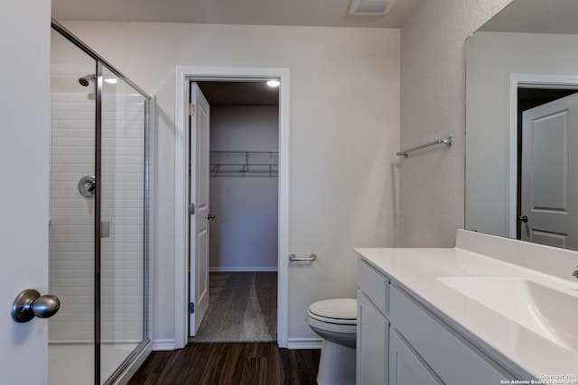 bathroom with toilet, vanity, a shower with door, and hardwood / wood-style floors