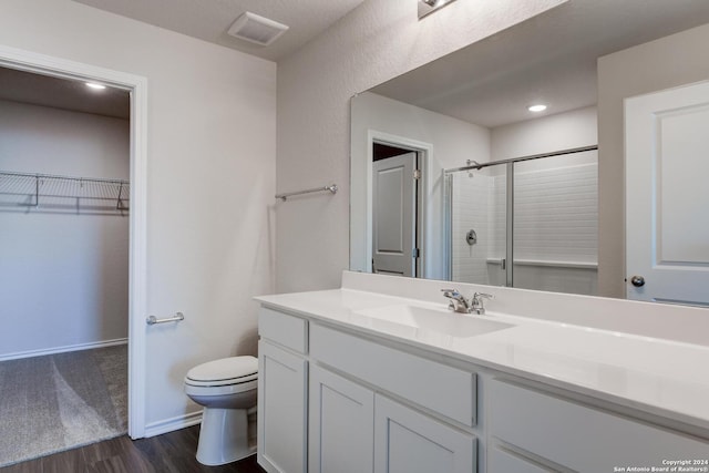 bathroom featuring hardwood / wood-style flooring, vanity, an enclosed shower, and toilet