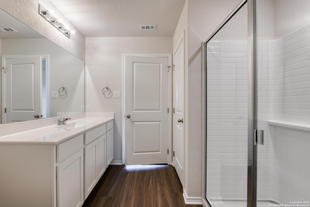 bathroom featuring hardwood / wood-style flooring, vanity, walk in shower, and a textured ceiling