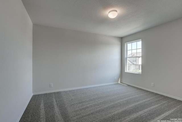 empty room featuring a textured ceiling and dark carpet