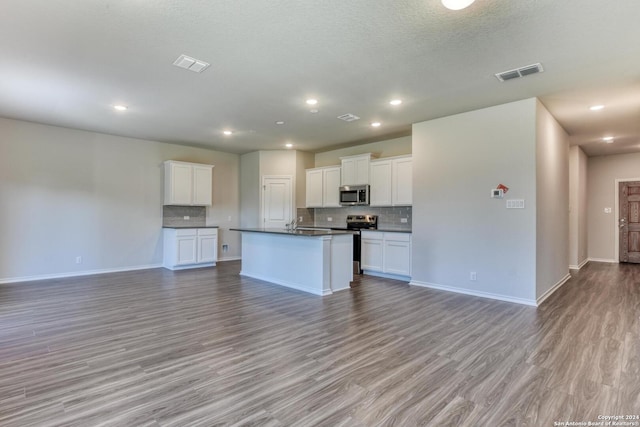 kitchen with stainless steel appliances, an island with sink, white cabinets, and light wood-type flooring