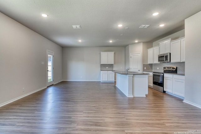 kitchen with white cabinetry, appliances with stainless steel finishes, a center island with sink, and light hardwood / wood-style floors