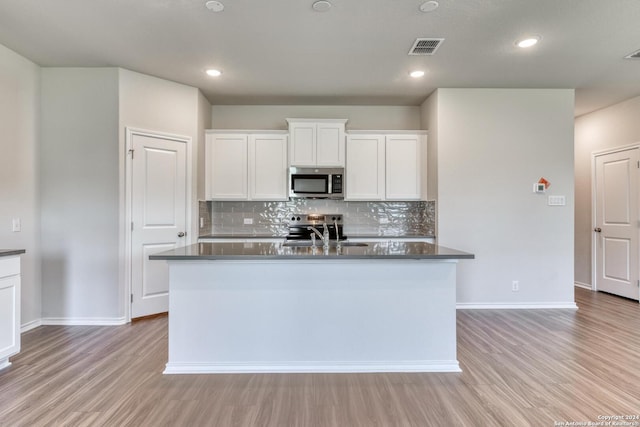 kitchen featuring sink, appliances with stainless steel finishes, an island with sink, white cabinets, and light wood-type flooring