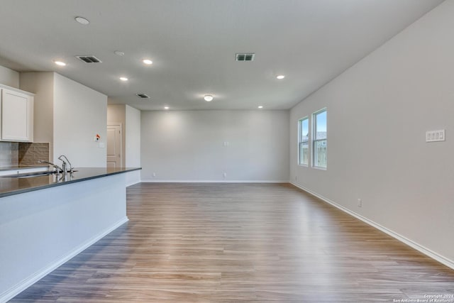 unfurnished living room with sink and light hardwood / wood-style flooring