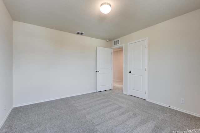 carpeted empty room featuring a textured ceiling