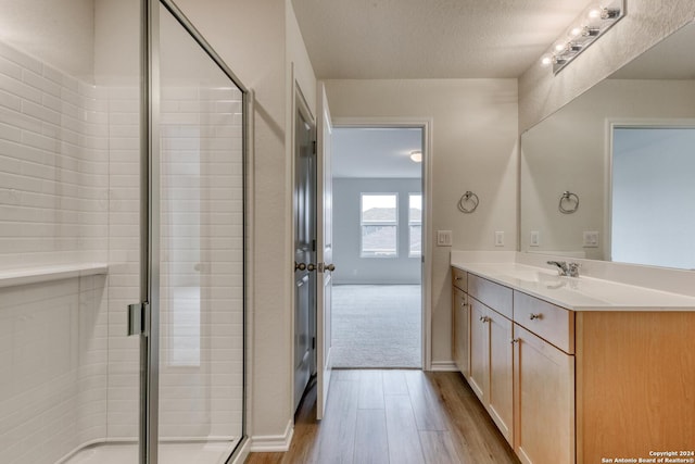 bathroom with a textured ceiling, vanity, wood-type flooring, and an enclosed shower