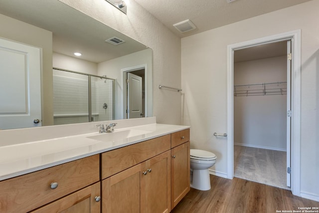 bathroom with hardwood / wood-style floors, vanity, toilet, walk in shower, and a textured ceiling