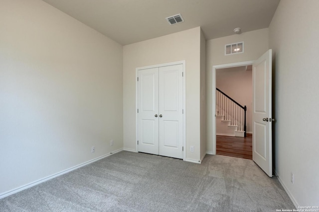 unfurnished bedroom featuring a closet and light colored carpet