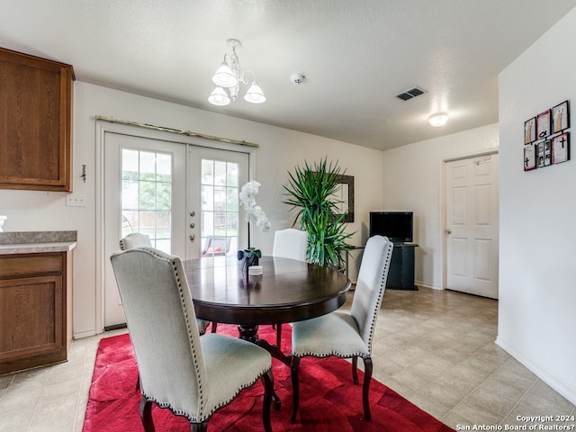 dining area featuring a chandelier, a textured ceiling, and french doors