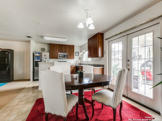 dining area featuring french doors, a textured ceiling, and an inviting chandelier