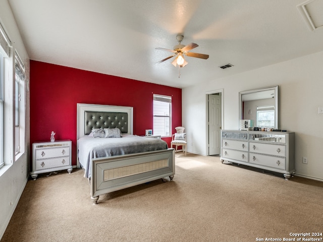 bedroom featuring multiple windows, ceiling fan, and light colored carpet