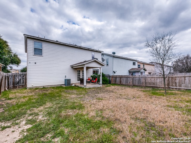 rear view of property featuring a yard, cooling unit, and a patio