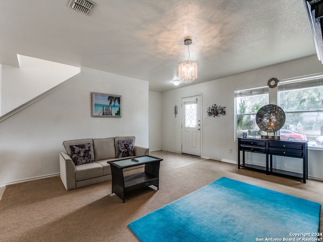 carpeted living room with a textured ceiling and a notable chandelier