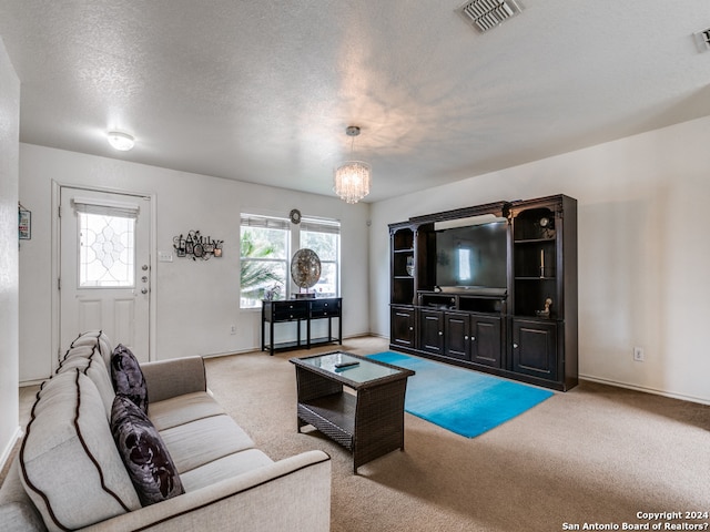 carpeted living room featuring a chandelier and a textured ceiling