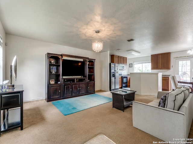 carpeted living room with a chandelier, a textured ceiling, and plenty of natural light