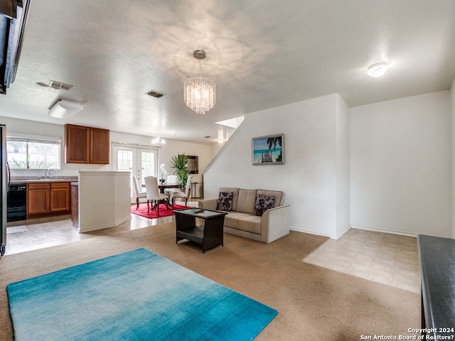 living room featuring a notable chandelier, sink, a textured ceiling, and light carpet