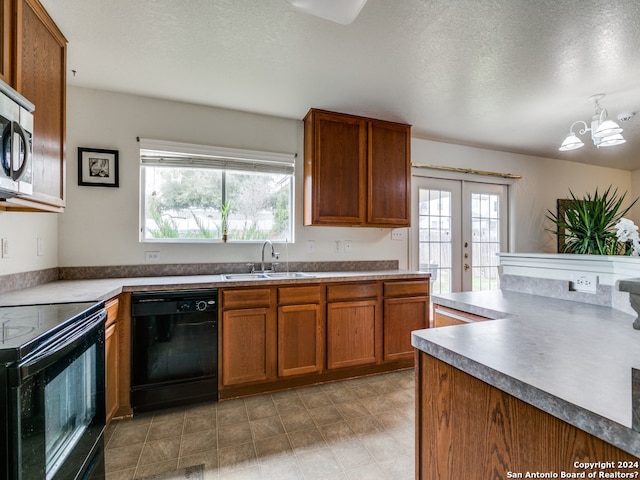 kitchen featuring black appliances, a healthy amount of sunlight, sink, and an inviting chandelier