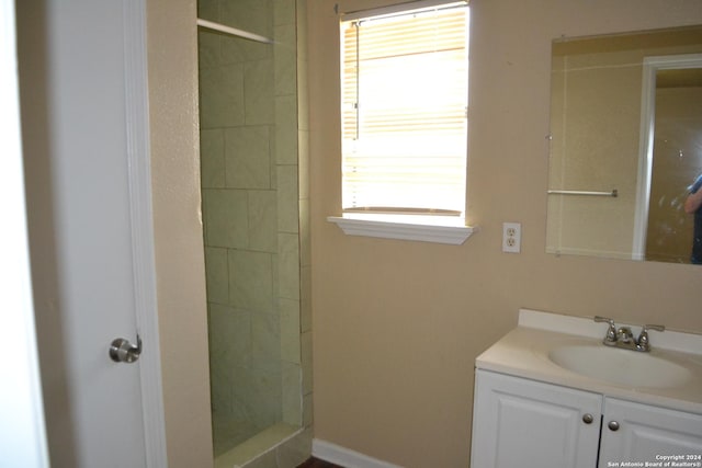 bathroom with a tile shower, a wealth of natural light, and vanity