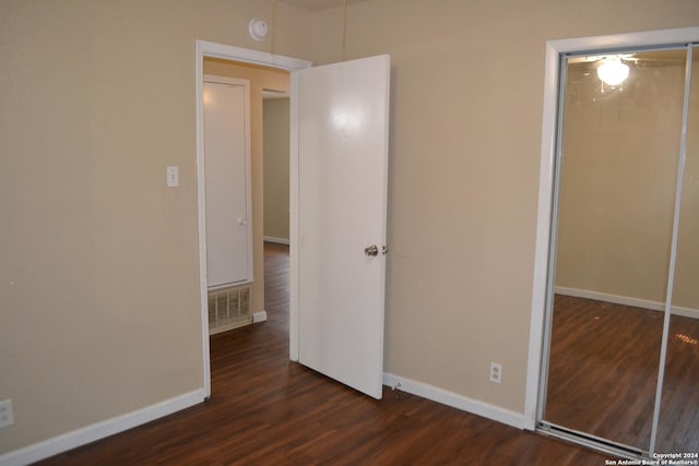 unfurnished bedroom with dark wood-type flooring and a closet