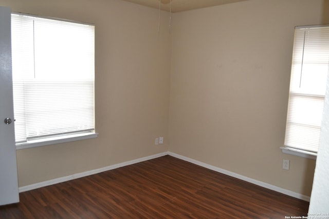 empty room with dark hardwood / wood-style flooring and a healthy amount of sunlight