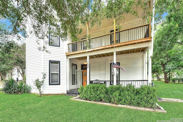 view of front of property with a porch, a balcony, and a front lawn