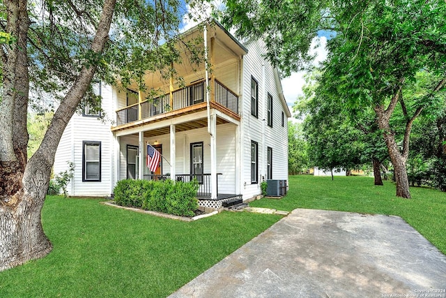 view of front facade featuring covered porch, a balcony, central AC, and a front lawn