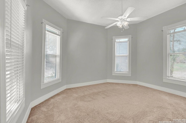 unfurnished room featuring ceiling fan, light colored carpet, and a textured ceiling